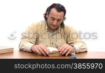 man sits at table and reads old book.