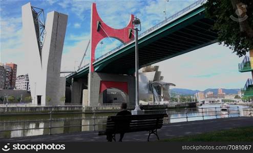 Man sits on a bench near the La Salve Bridge in Bilbao,Spain