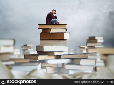 Man sits on a stack of books. Lots of books around. Gaining knowledge and education concept. Student reading. Man sits on a stack of books
