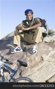 Man sits on rock wearing cycling helmet