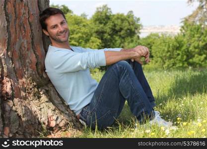 Man sitting against tree
