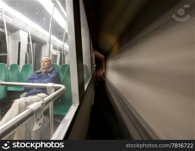 Man, sitting alone in a metro, driving at speed through a tunnel