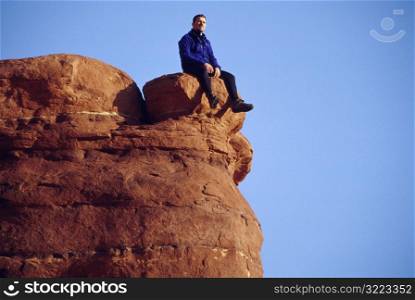 Man Sitting Alone On A Giant Red Rock