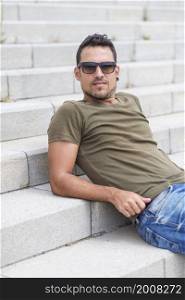 Man sitting alone on steps. Handsome boy with sunglasses