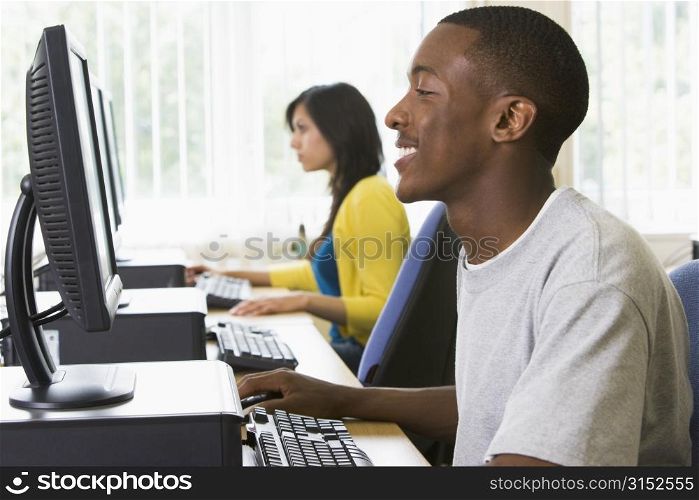 Man sitting at a computer terminal with woman in background (selective focus/high key)