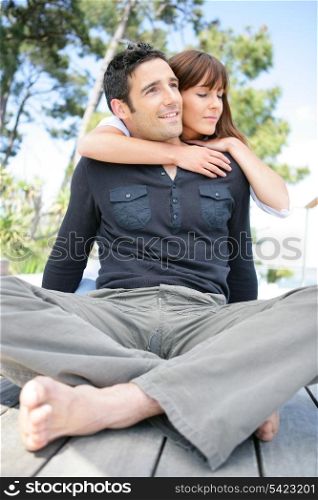 Man sitting cross-legged and being hugged by his wife