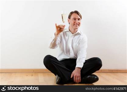 Man sitting cross-legged on the wooden floor of his apartment