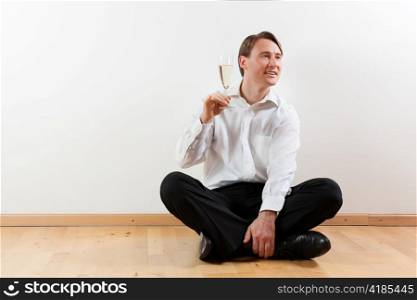 Man sitting cross-legged on the wooden floor of his apartment