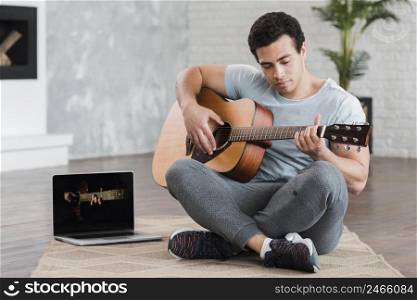 man sitting floor learning how play guitar