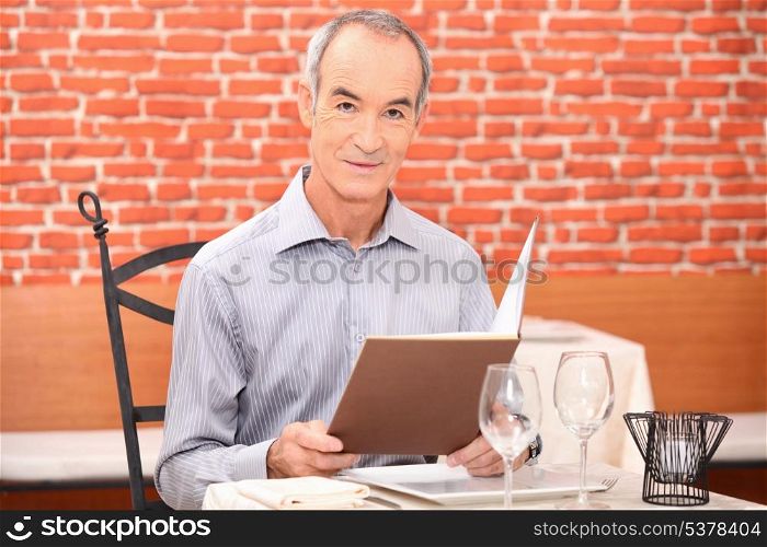 man sitting in a restaurant reading the menu