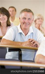 Man sitting in adult classroom with students in background (selective focus)