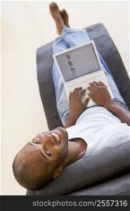 Man sitting in chair using laptop smiling