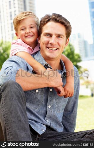Man sitting in city park with young son