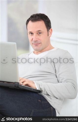 Man sitting in couch using laptop computer