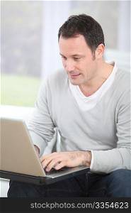 Man sitting in couch using laptop computer