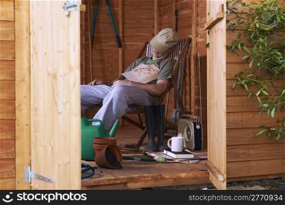 Man sitting in deckchair falling asleep in the shed