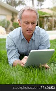 Man sitting in home garden with touchpad