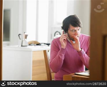 Man sitting in kitchen using phone