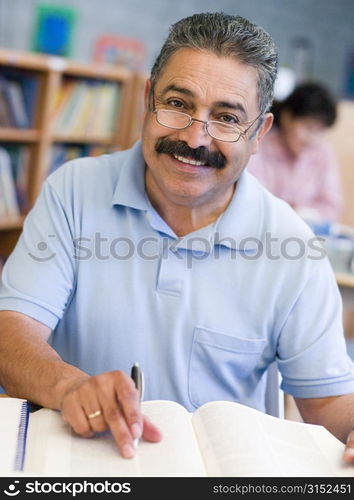 Man sitting in library with a book and notepad (selective focus)