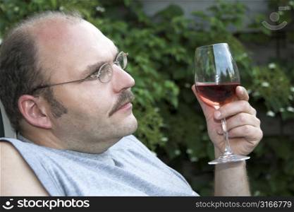 Man sitting in the garden enjoying a glass of wine and overthinking his life