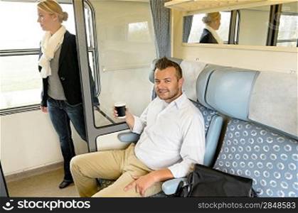 Man sitting in train woman on hallway coffee commuters smiling