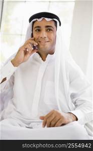 Man sitting indoors on cellular phone smiling (high key)