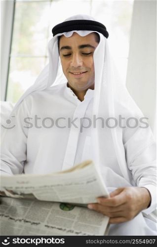 Man sitting indoors with newspaper smiling (high key/selective focus)