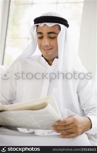 Man sitting indoors with newspaper smiling (high key/selective focus)
