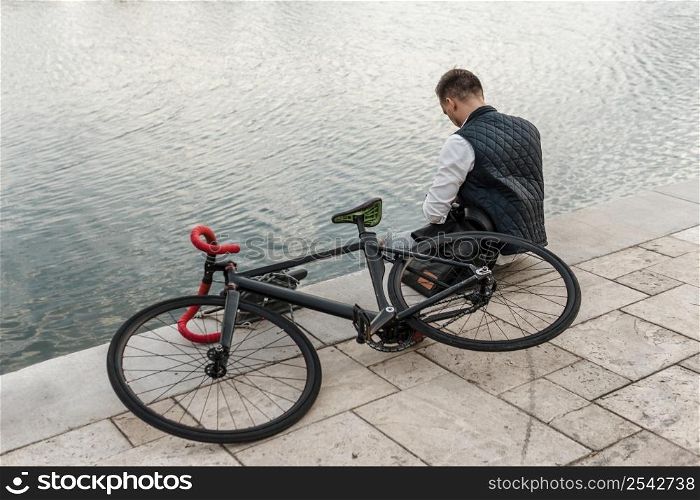 man sitting lake with his bike