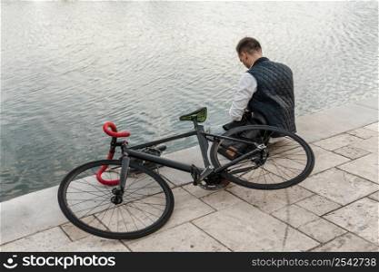 man sitting lake with his bike