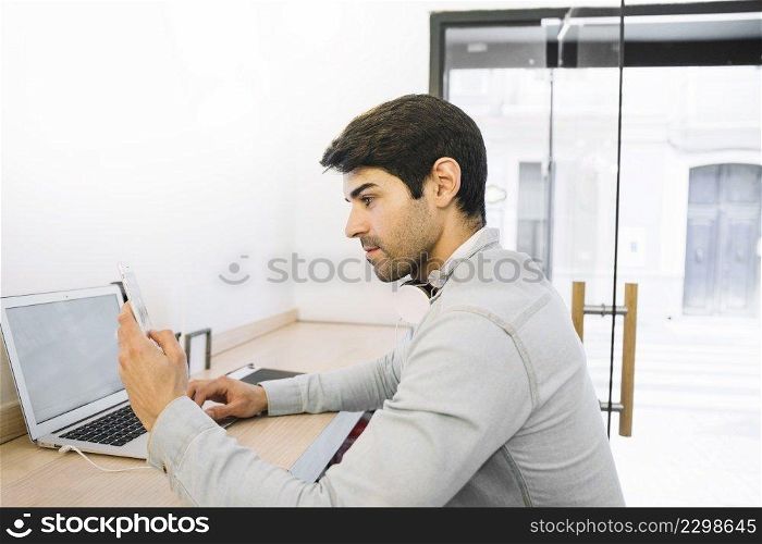 man sitting laptop using smartphone