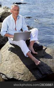 Man sitting on a rock with his laptop