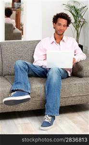 Man sitting on a sofa and typing on his laptop