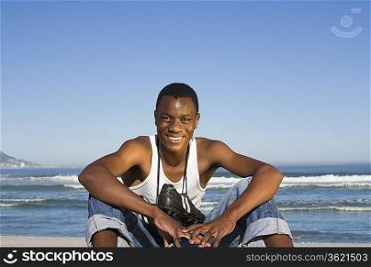 Man sitting on beach with with football boots round his neck