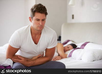 Man Sitting On Bed And Feeling Unwell