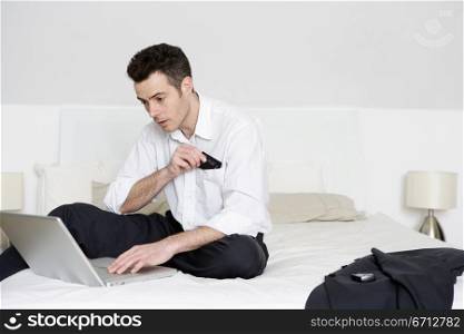man sitting on bed with laptop spending on-line