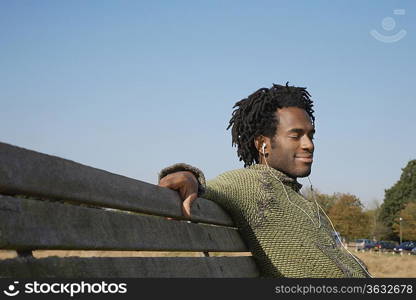 Man sitting on bench listening to music from earphones