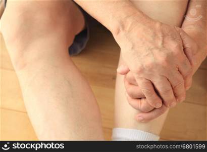 Man sitting on floor with both hands on a leg