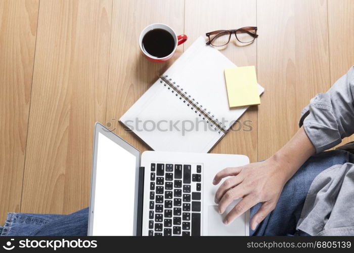 man sitting on floor with laptop computer, coffee cup and eyeglasses - top view