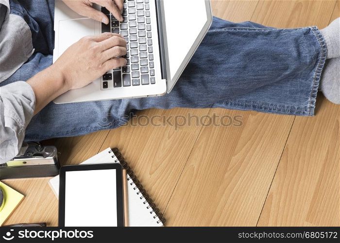 man sitting on floor with laptop computer, coffee cup and tablet