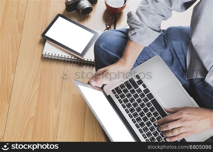 man sitting on floor with laptop computer, coffee cup and tablet - top view