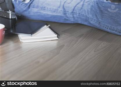 man sitting on floor with tablet, notebook and pencil