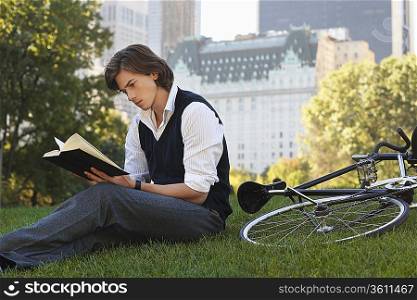 Man sitting on lawn, reading book