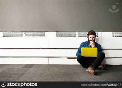 Man sitting on office floor with laptop