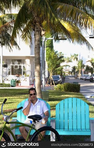 Man sitting on patio chair talking on cell phone