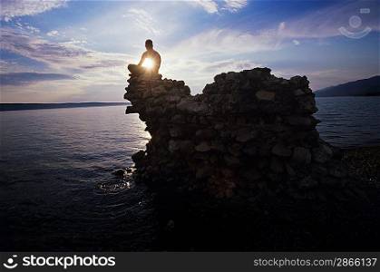 Man sitting on rock overlooking ocean