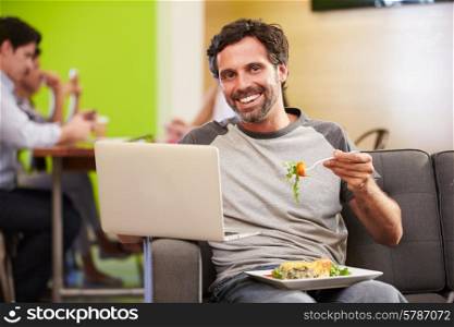 Man Sitting On Sofa And Eating Lunch In Design Studio