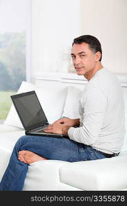 Man sitting on sofa at home with laptop computer