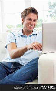 Man Sitting On Sofa Using Laptop At Home
