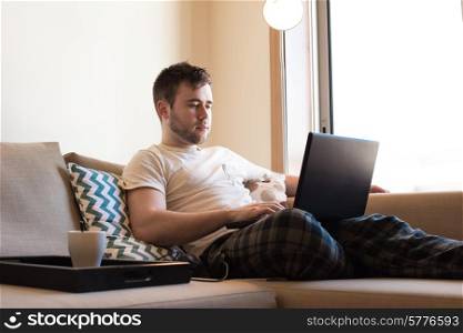 Man sitting on sofa with laptop and a cup of coffee